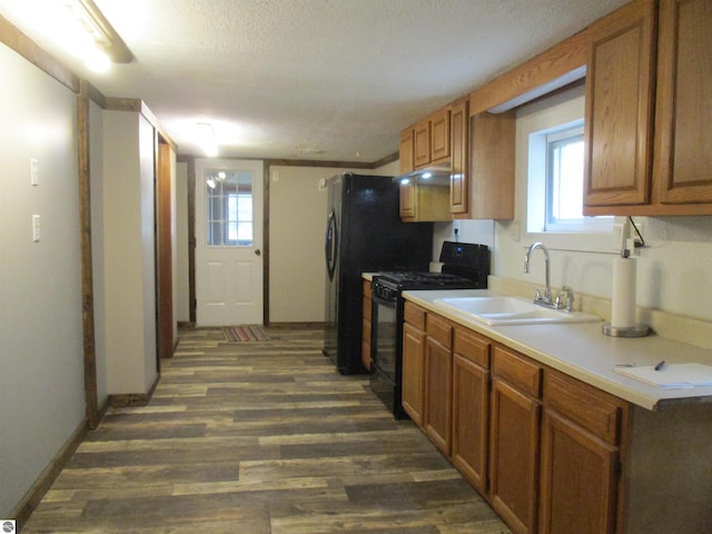 kitchen featuring a textured ceiling, gas stove, dark hardwood / wood-style flooring, and sink