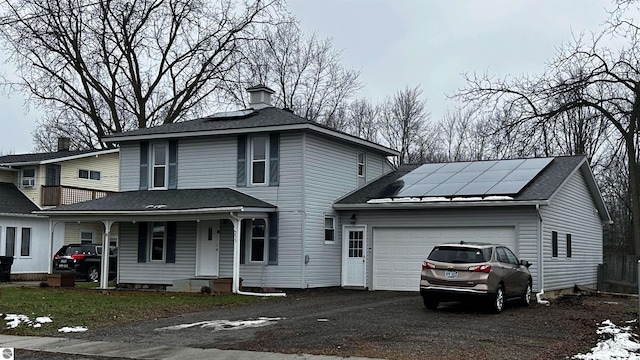 view of front property with covered porch, solar panels, and a garage