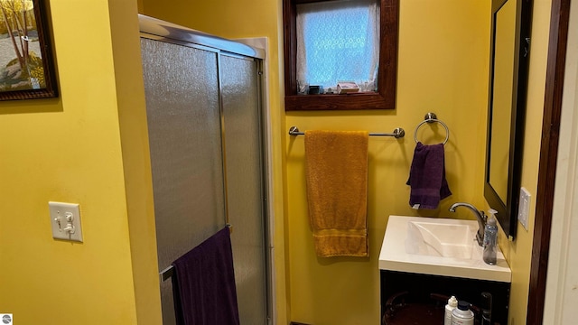 bathroom featuring a shower with door and vanity