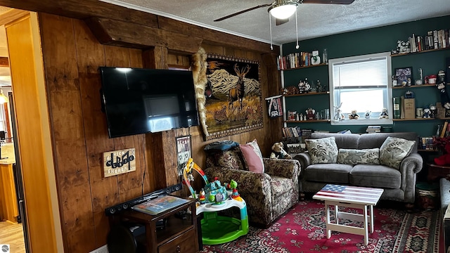 living room featuring wooden walls, ceiling fan, and a textured ceiling