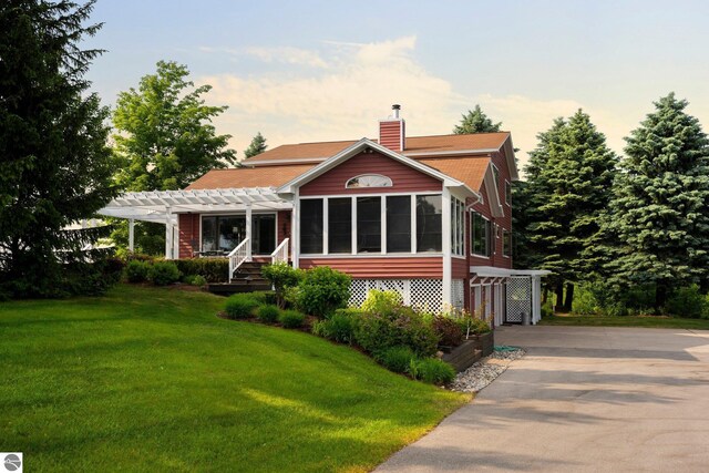 10343 E Hilltop Rd, Suttons Bay, MI 49682 - view of front of house featuring a pergola, a sunroom, and a lawn