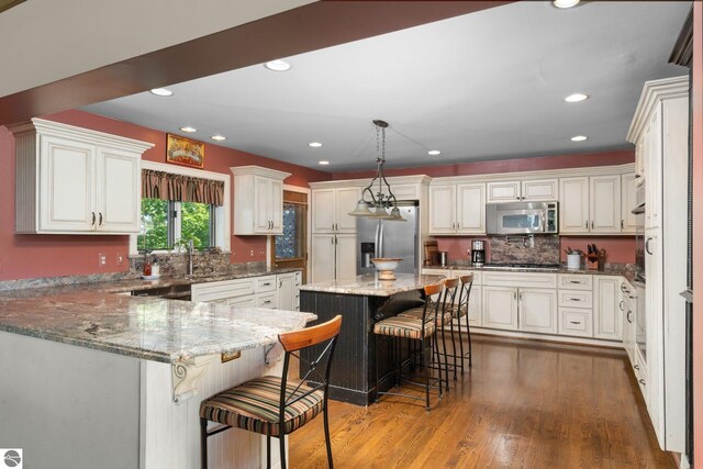 10343 E Hilltop Rd, Suttons Bay, MI 49682 - kitchen featuring a kitchen breakfast bar, dark hardwood / wood-style floors, decorative light fixtures, a kitchen island, and stainless steel appliances