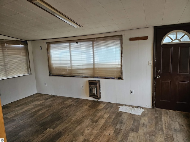 foyer entrance with plenty of natural light, wood walls, dark wood-type flooring, and heating unit