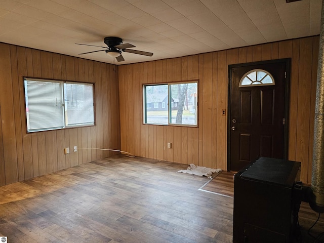 foyer entrance with hardwood / wood-style flooring, ceiling fan, and wood walls