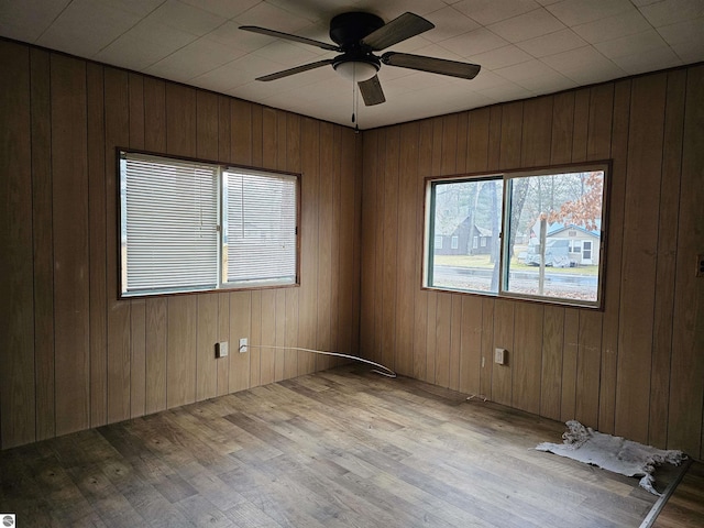 empty room featuring light hardwood / wood-style floors, ceiling fan, and wooden walls