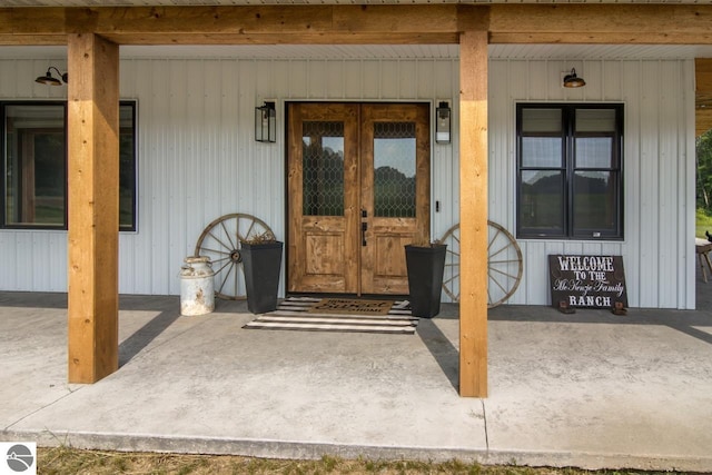 view of exterior entry featuring french doors and a porch