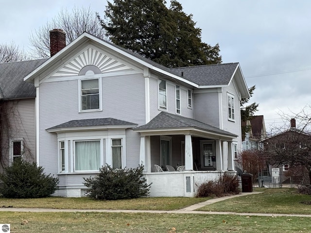 front facade featuring covered porch and a front lawn