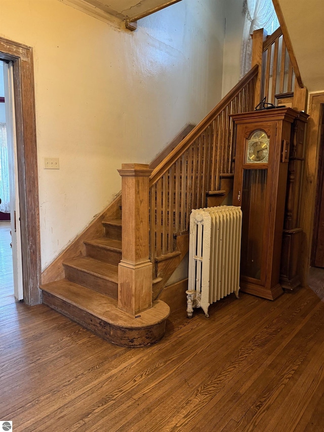 stairs featuring radiator heating unit and hardwood / wood-style floors