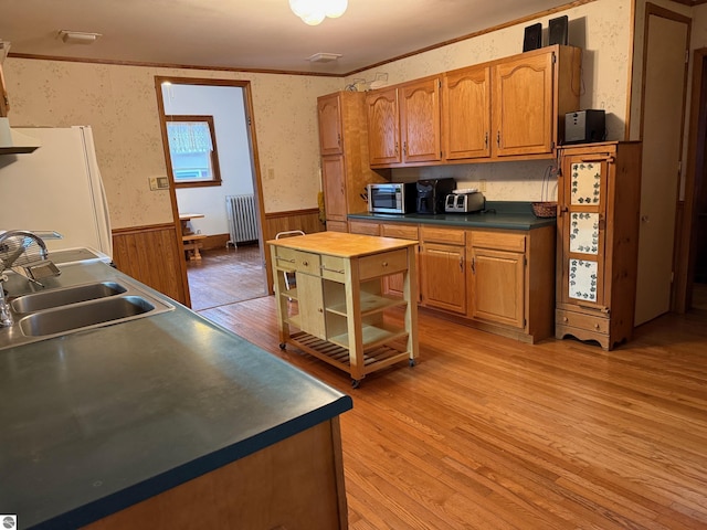 kitchen featuring radiator, white refrigerator, crown molding, sink, and light hardwood / wood-style flooring