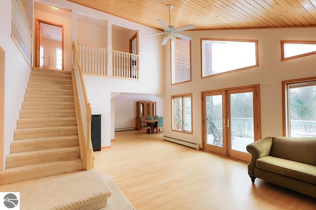 living room featuring french doors, a high ceiling, baseboard heating, light hardwood / wood-style floors, and wood ceiling