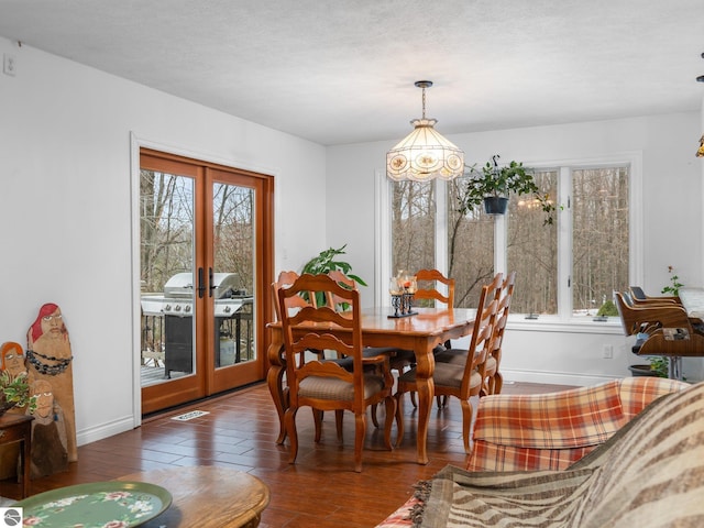 dining room featuring a wealth of natural light, french doors, dark wood-type flooring, and a notable chandelier