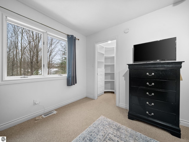 carpeted bedroom with a walk in closet and a closet