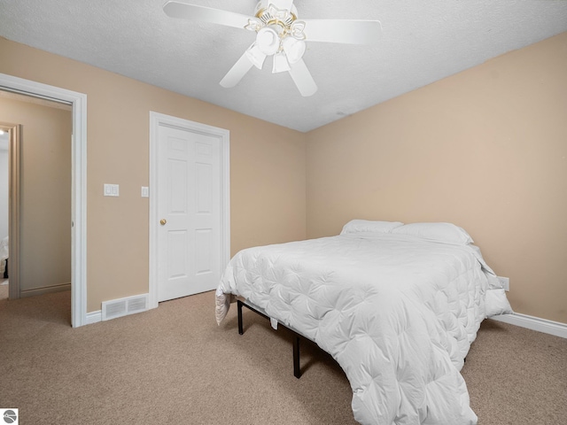 bedroom featuring ceiling fan, carpet floors, and a textured ceiling