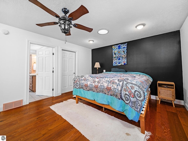 bedroom featuring ceiling fan, wood-type flooring, and a textured ceiling