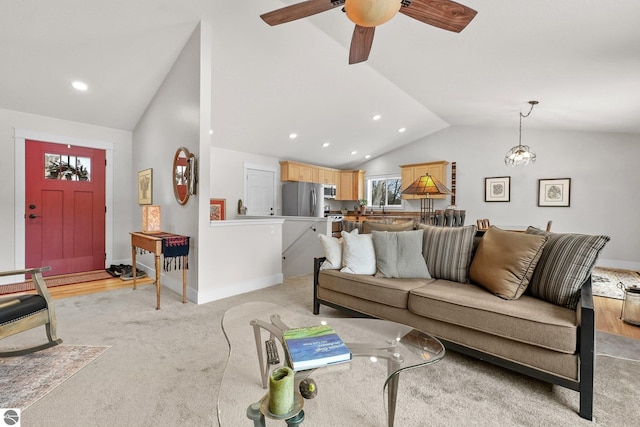 carpeted living room featuring ceiling fan with notable chandelier and vaulted ceiling