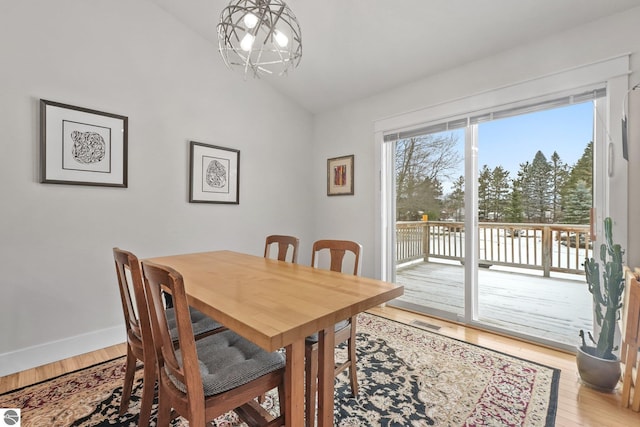 dining space with a chandelier, lofted ceiling, and hardwood / wood-style flooring