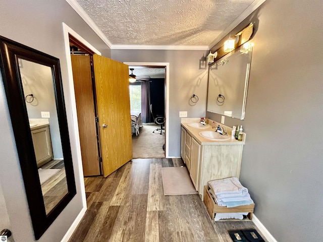 bathroom featuring ceiling fan, crown molding, hardwood / wood-style floors, a textured ceiling, and vanity