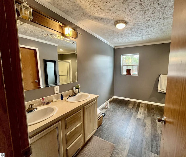 bathroom featuring vanity, a textured ceiling, hardwood / wood-style flooring, and ornamental molding