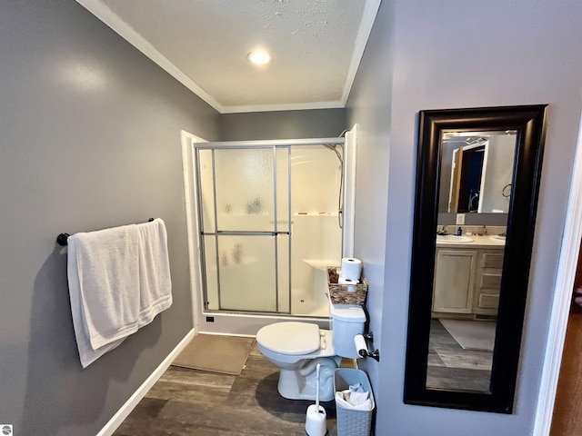 bathroom with ornamental molding, vanity, hardwood / wood-style flooring, toilet, and a shower with shower door