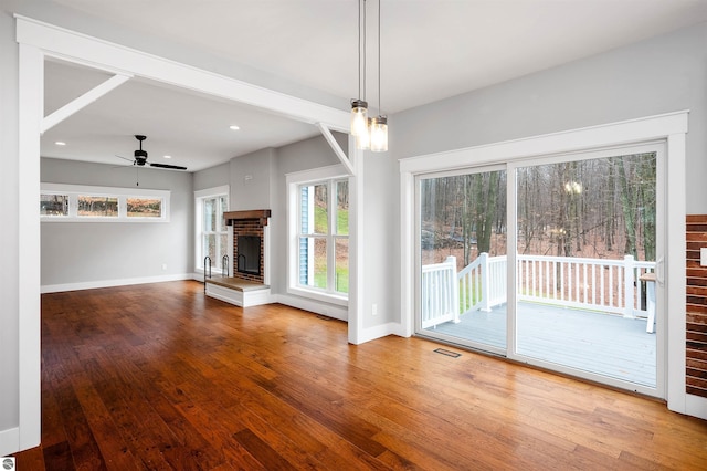 unfurnished living room with ceiling fan, a healthy amount of sunlight, and hardwood / wood-style flooring