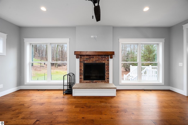 unfurnished living room featuring a fireplace, light hardwood / wood-style flooring, ceiling fan, and a healthy amount of sunlight