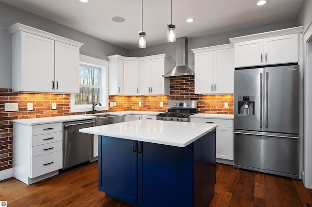 kitchen featuring white cabinets, a center island, wall chimney range hood, and appliances with stainless steel finishes