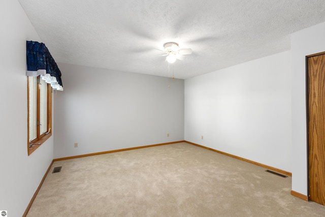 unfurnished room featuring ceiling fan, light colored carpet, and a textured ceiling