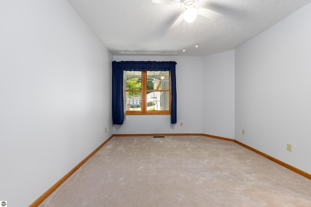 empty room featuring ceiling fan, light colored carpet, and a textured ceiling