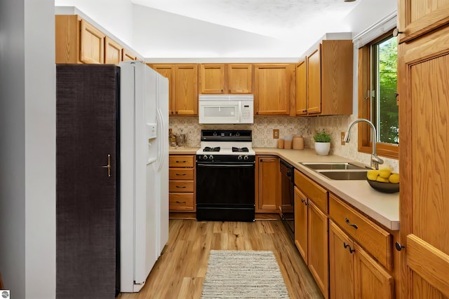 kitchen with white appliances, sink, light hardwood / wood-style flooring, vaulted ceiling, and decorative backsplash