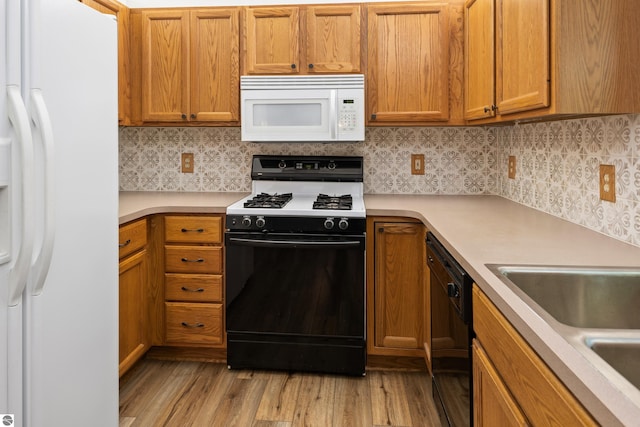 kitchen featuring backsplash, light hardwood / wood-style flooring, white appliances, and sink