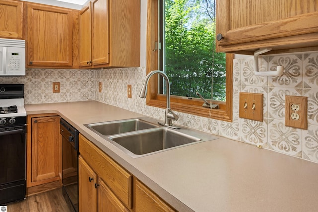 kitchen featuring decorative backsplash, sink, light hardwood / wood-style flooring, and black appliances