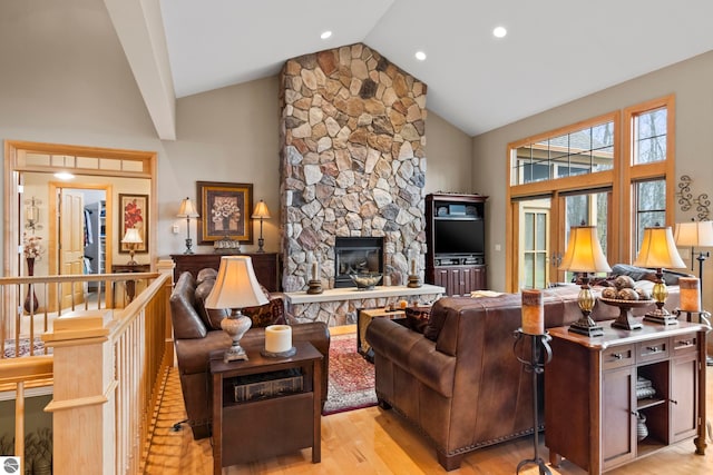 living room with light wood-type flooring, a fireplace, and high vaulted ceiling