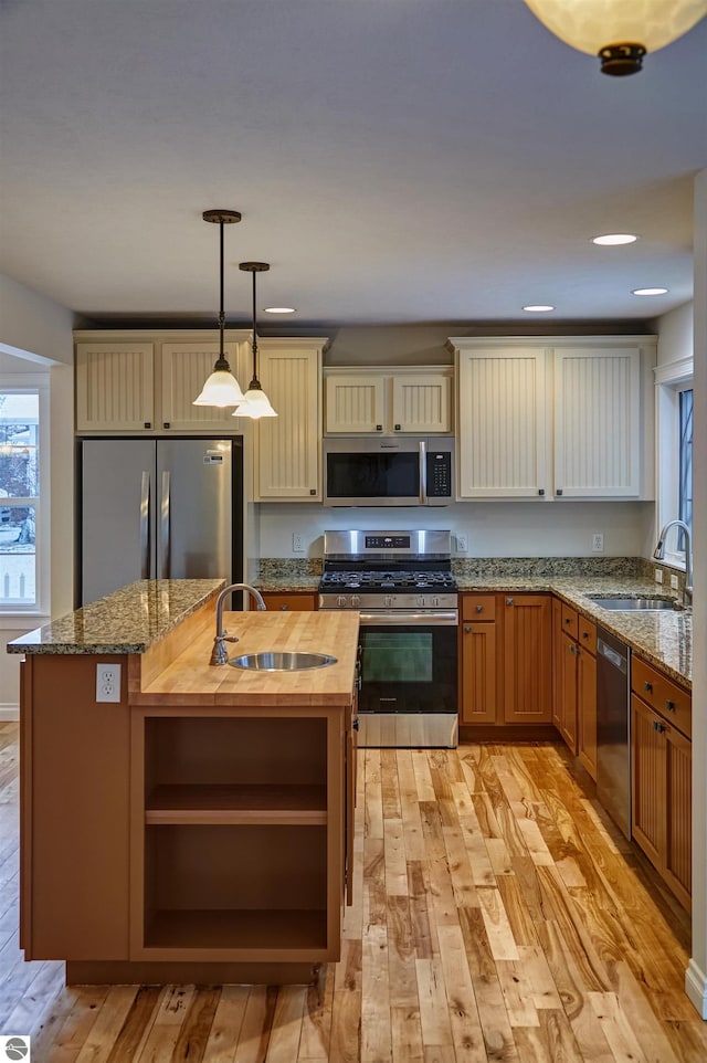 kitchen featuring wood counters, appliances with stainless steel finishes, hanging light fixtures, and sink