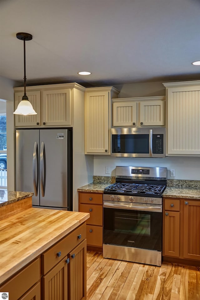 kitchen with pendant lighting, wood counters, light hardwood / wood-style floors, and stainless steel appliances