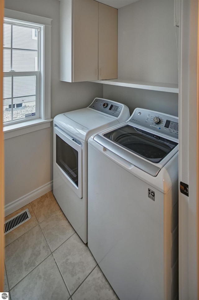 clothes washing area featuring cabinets, independent washer and dryer, and light tile patterned flooring