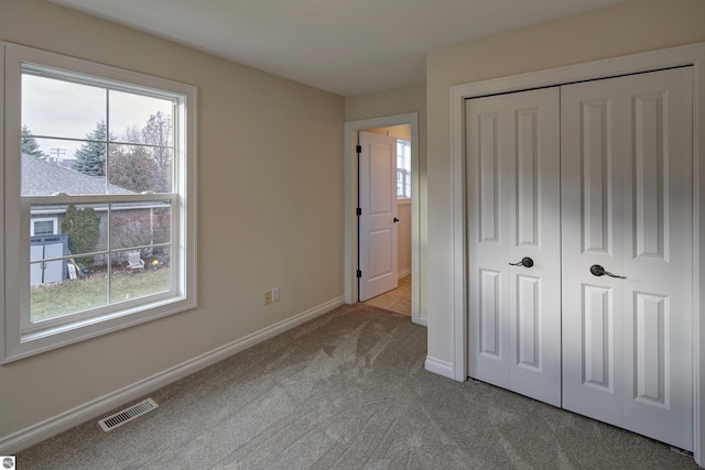 unfurnished bedroom featuring light colored carpet and a closet