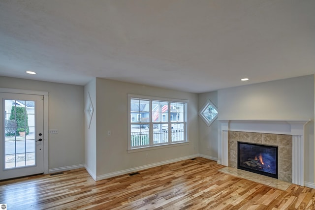 unfurnished living room with light hardwood / wood-style flooring and a tiled fireplace