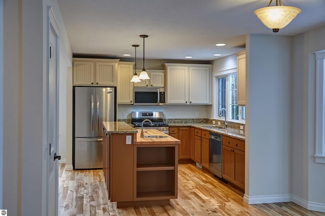 kitchen featuring appliances with stainless steel finishes, sink, hanging light fixtures, and an island with sink