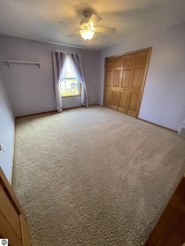 unfurnished bedroom featuring carpet floors, a closet, and ceiling fan