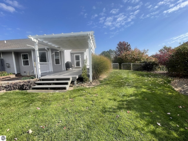 rear view of house with a pergola, a lawn, and a deck