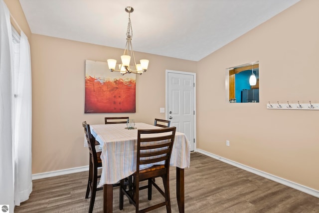 dining area featuring lofted ceiling, dark hardwood / wood-style flooring, and a notable chandelier