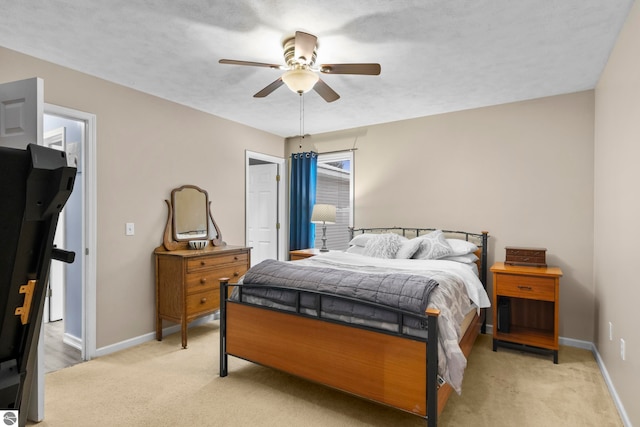 bedroom with ceiling fan, light colored carpet, and a spacious closet