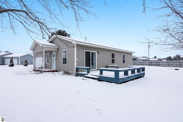 snow covered rear of property featuring a garage