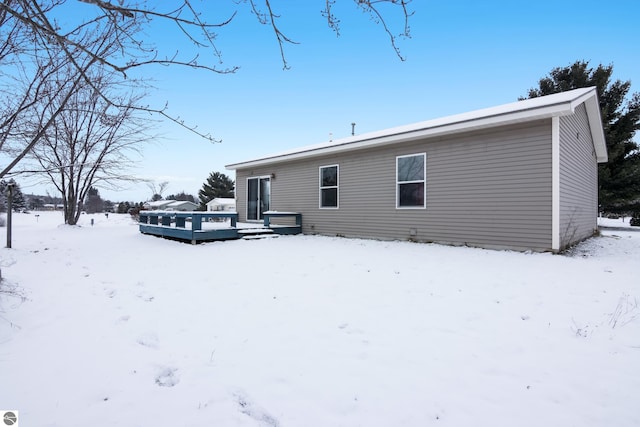 snow covered back of property with a wooden deck