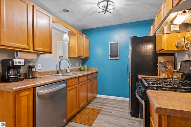 kitchen featuring pendant lighting, black gas stove, sink, stainless steel dishwasher, and extractor fan