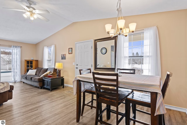 dining area with vaulted ceiling, a healthy amount of sunlight, light hardwood / wood-style floors, and ceiling fan with notable chandelier