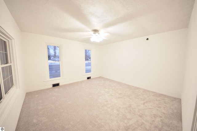 empty room featuring carpet, ceiling fan, and a textured ceiling