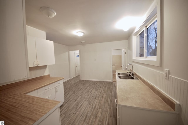 kitchen with hardwood / wood-style flooring, white cabinetry, and sink