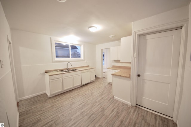 kitchen with light hardwood / wood-style flooring, white cabinetry, and sink