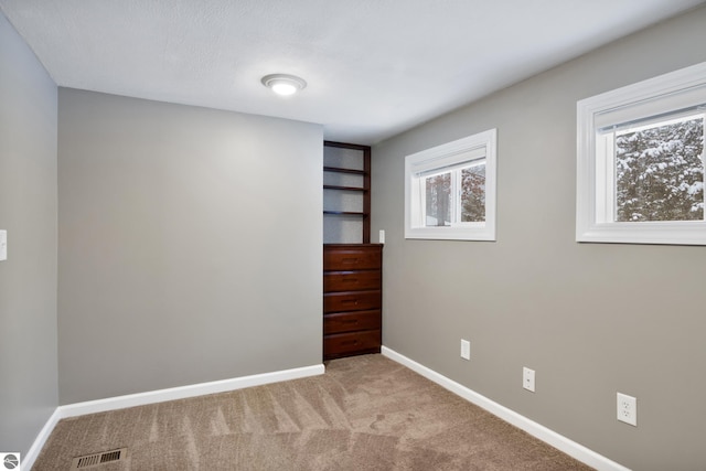 unfurnished bedroom with light colored carpet and multiple windows